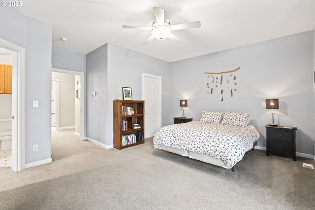 bedroom with ceiling fan, light colored carpet, and ensuite bathroom