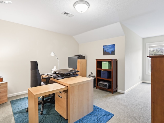 carpeted home office with vaulted ceiling