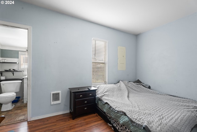 bedroom featuring ensuite bathroom, dark hardwood / wood-style flooring, and heating unit