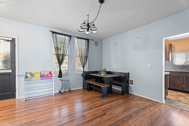 dining space featuring wood-type flooring, sink, and an inviting chandelier