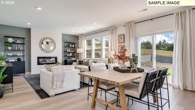 dining area featuring a large fireplace, recessed lighting, visible vents, and light wood-style floors