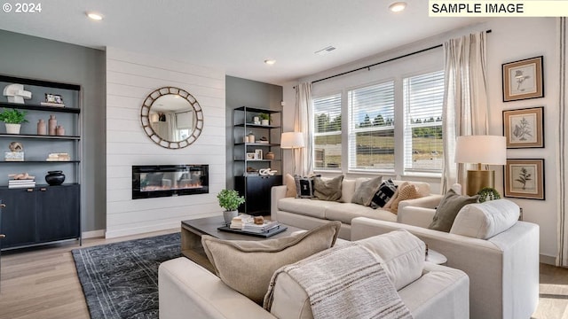 living area with light wood-type flooring, a large fireplace, baseboards, and recessed lighting