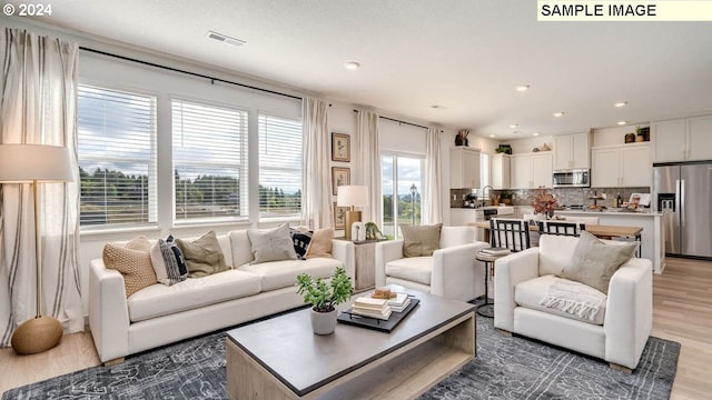 living area featuring visible vents, light wood-style flooring, and recessed lighting