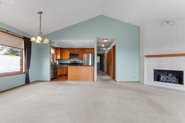 kitchen with light colored carpet, hanging light fixtures, a brick fireplace, and stainless steel appliances