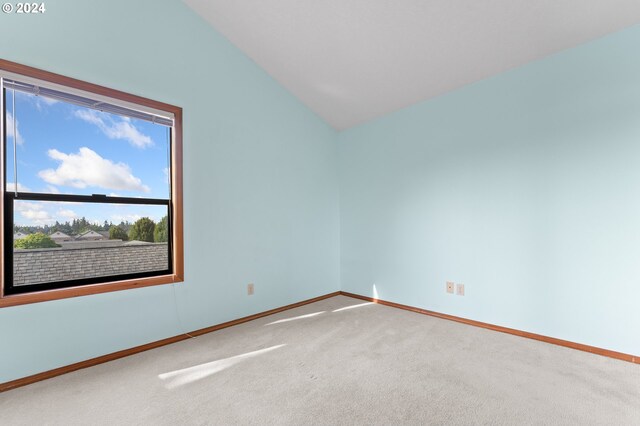 carpeted spare room with vaulted ceiling