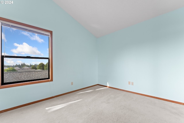 carpeted empty room featuring baseboards and vaulted ceiling