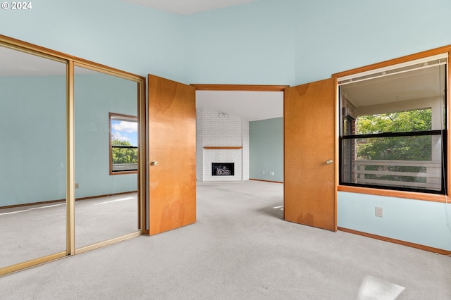 unfurnished room featuring a fireplace, baseboards, and light colored carpet