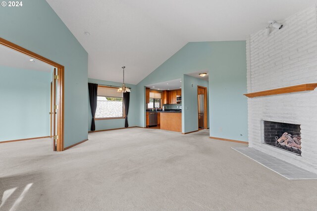 unfurnished living room featuring a large fireplace, brick wall, high vaulted ceiling, a notable chandelier, and light carpet