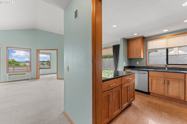 kitchen featuring stainless steel dishwasher, sink, vaulted ceiling, light carpet, and a wall unit AC