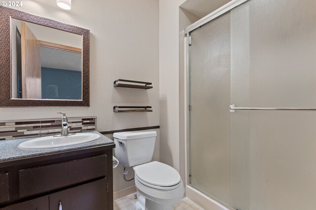 bathroom featuring backsplash, tile patterned floors, vanity, toilet, and a shower with door