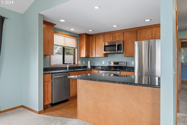 kitchen featuring recessed lighting, stainless steel appliances, a sink, baseboards, and dark stone countertops