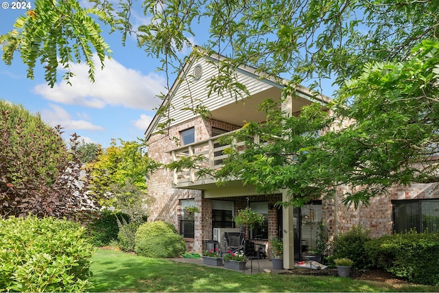 back of property featuring a balcony, a lawn, and brick siding