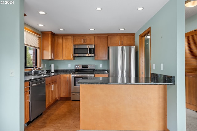 kitchen with dark stone counters, stainless steel appliances, a sink, and recessed lighting