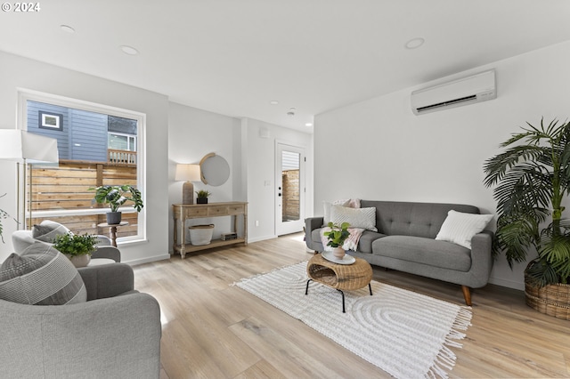 living room featuring an AC wall unit, a wealth of natural light, and light hardwood / wood-style flooring