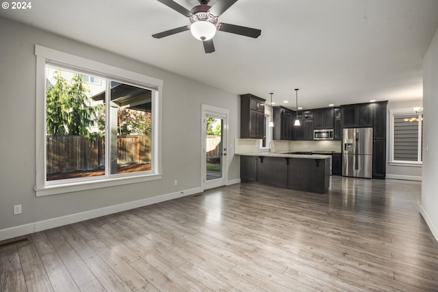 kitchen featuring appliances with stainless steel finishes, kitchen peninsula, light hardwood / wood-style floors, and ceiling fan