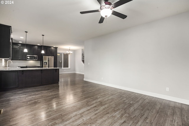 kitchen with ceiling fan with notable chandelier, backsplash, appliances with stainless steel finishes, and dark hardwood / wood-style floors