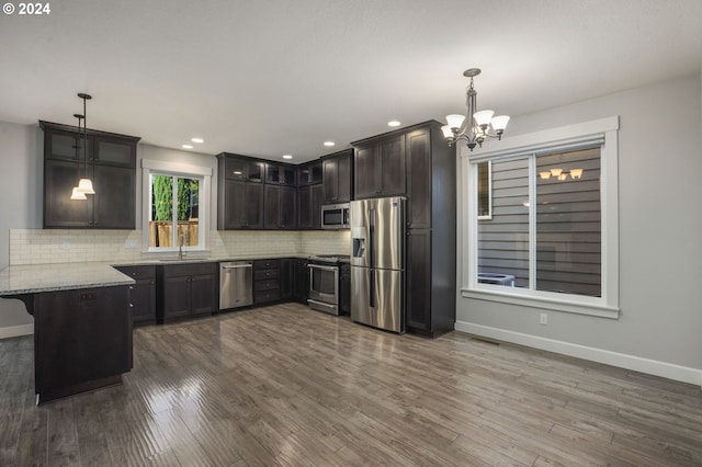 kitchen featuring pendant lighting, a notable chandelier, appliances with stainless steel finishes, and hardwood / wood-style flooring