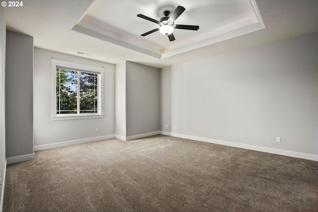 unfurnished room with ceiling fan, a raised ceiling, ornamental molding, and carpet