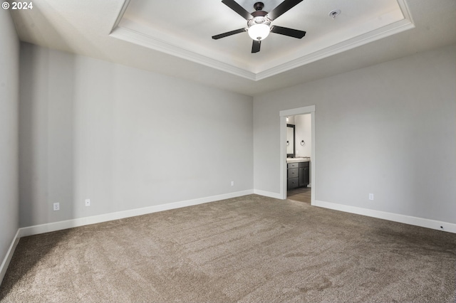 carpeted spare room with a tray ceiling and ceiling fan