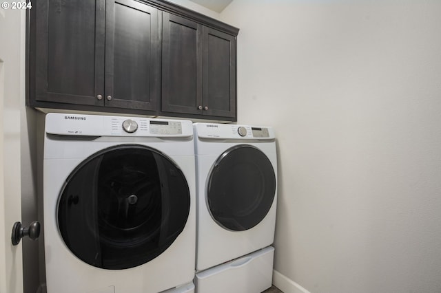 laundry room featuring washer and clothes dryer and cabinets