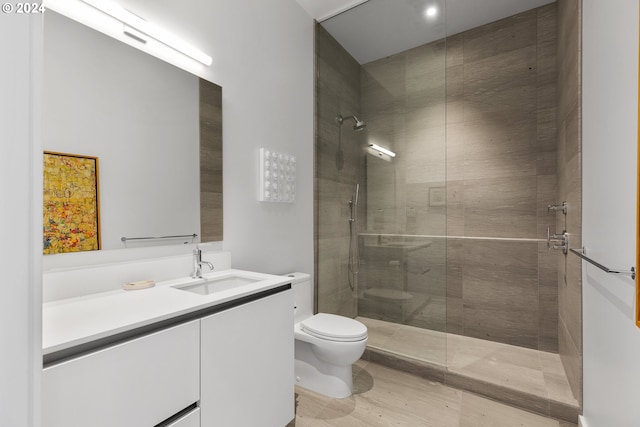 bathroom with vanity, a tile shower, and toilet