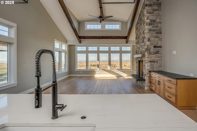 unfurnished living room with high vaulted ceiling, a fireplace, and light hardwood / wood-style flooring