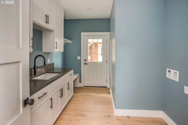 interior space featuring sink, light hardwood / wood-style floors, and white cabinets