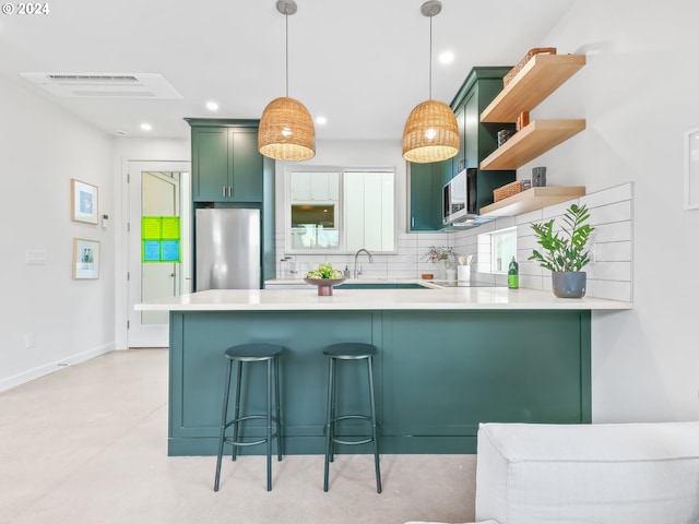 kitchen featuring appliances with stainless steel finishes, decorative light fixtures, tasteful backsplash, a kitchen breakfast bar, and kitchen peninsula