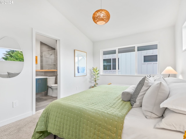 carpeted bedroom with ensuite bath and lofted ceiling