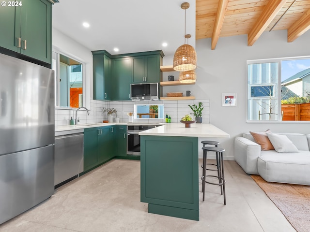 kitchen with a kitchen bar, green cabinets, and appliances with stainless steel finishes