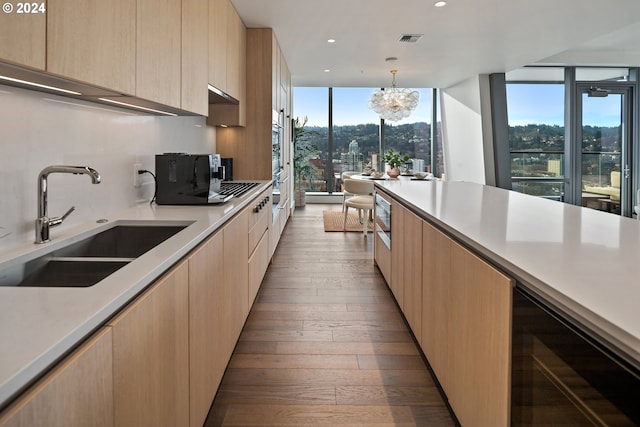 kitchen featuring light brown cabinets, a sink, visible vents, a wall of windows, and modern cabinets