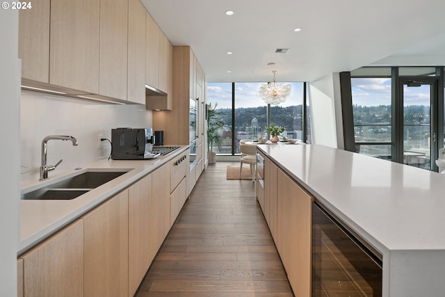 kitchen with beverage cooler, modern cabinets, a sink, and light brown cabinets