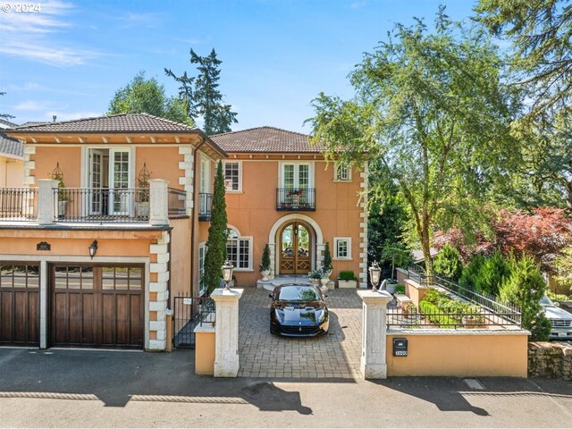 mediterranean / spanish home featuring a balcony, a garage, and french doors