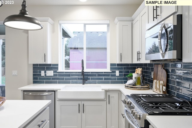 kitchen featuring sink, stainless steel appliances, decorative light fixtures, decorative backsplash, and white cabinets