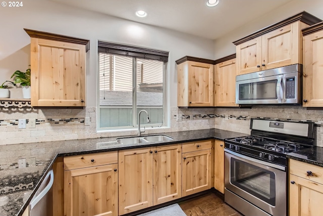 kitchen featuring dark stone counters, appliances with stainless steel finishes, tasteful backsplash, and sink