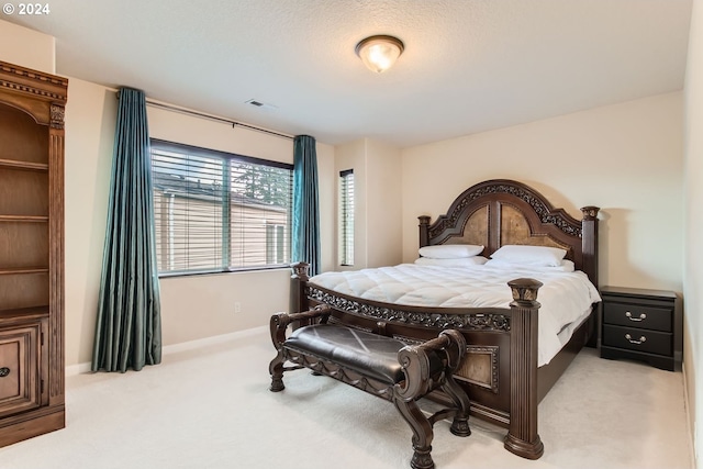 bedroom with a textured ceiling and light colored carpet