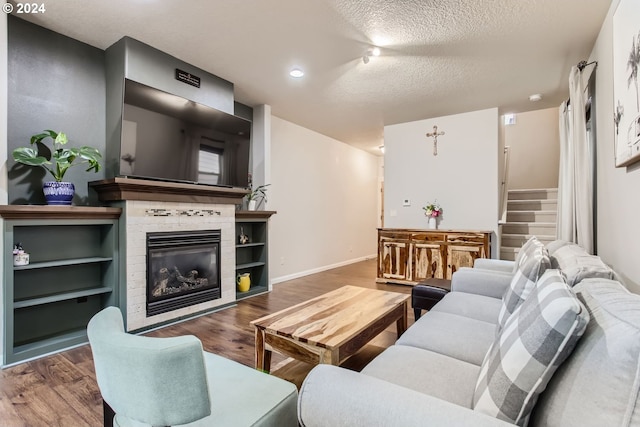 living room featuring hardwood / wood-style floors, a textured ceiling, and a fireplace