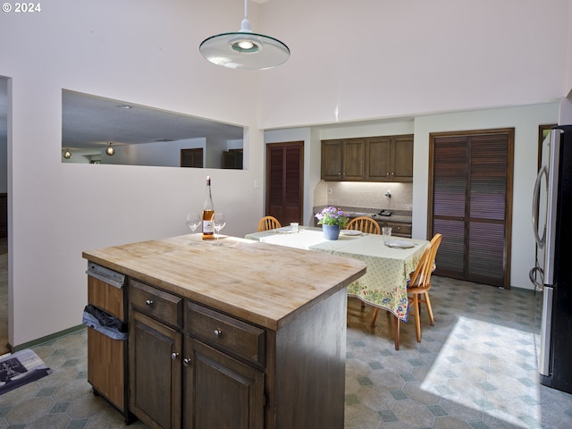 kitchen featuring dark brown cabinets, wooden counters, fridge, and a kitchen island