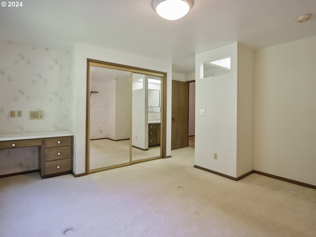 unfurnished bedroom with built in desk and light carpet