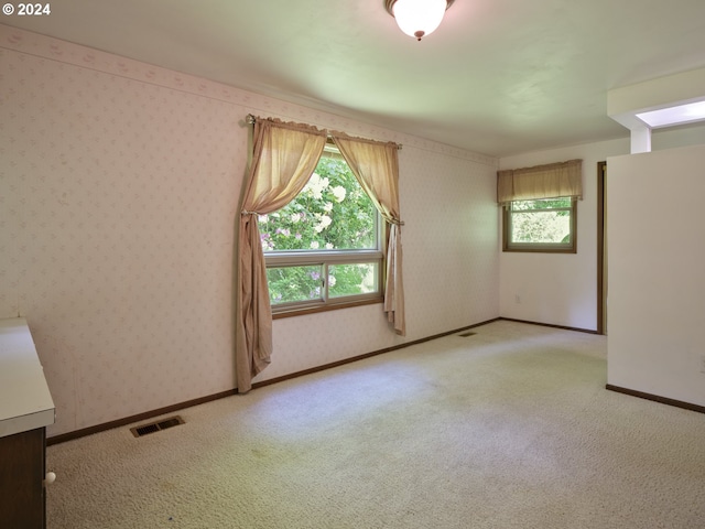 unfurnished room with light colored carpet and a healthy amount of sunlight