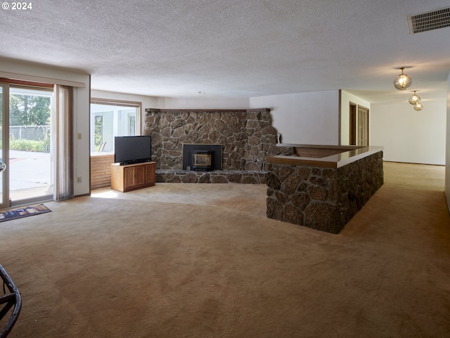 carpeted living room with a wood stove and a textured ceiling