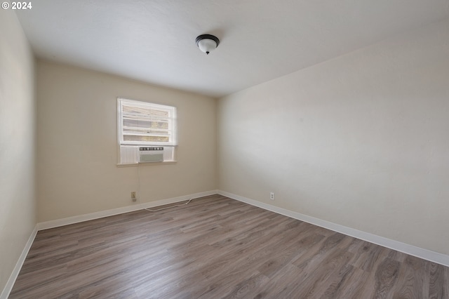 spare room with cooling unit and wood-type flooring