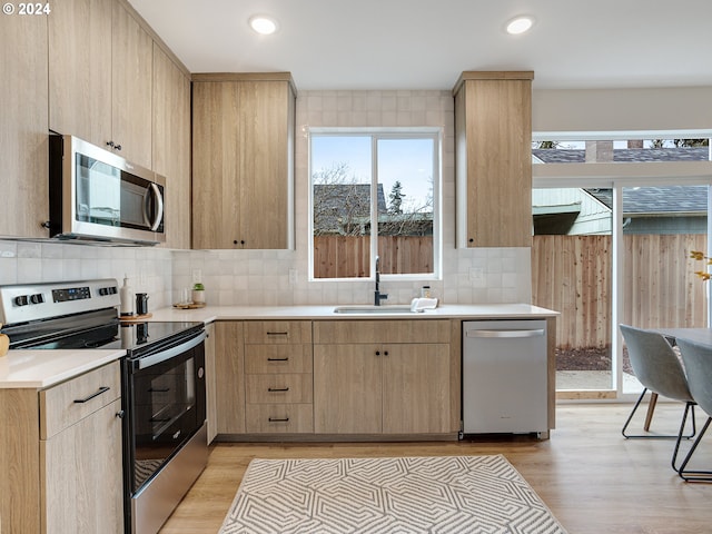 kitchen featuring light brown cabinets, stainless steel appliances, light hardwood / wood-style flooring, backsplash, and sink