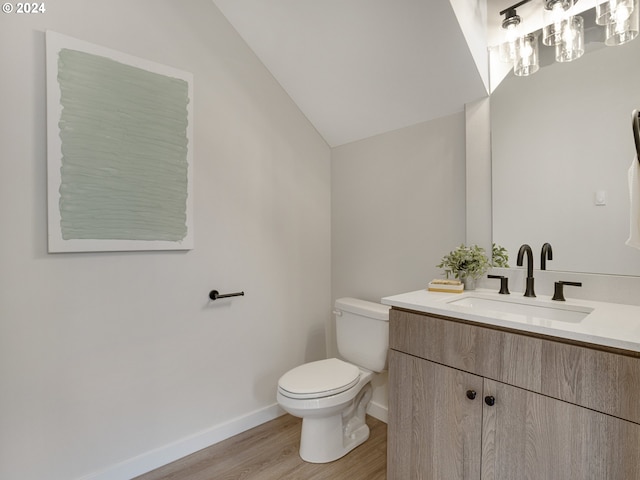 bathroom featuring vanity, toilet, hardwood / wood-style flooring, and vaulted ceiling