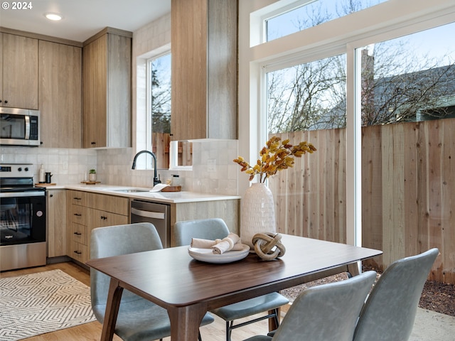 kitchen featuring light brown cabinets, appliances with stainless steel finishes, light wood-type flooring, backsplash, and sink