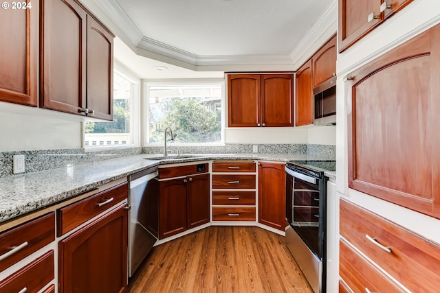 kitchen featuring light stone counters, stainless steel appliances, a sink, light wood finished floors, and crown molding