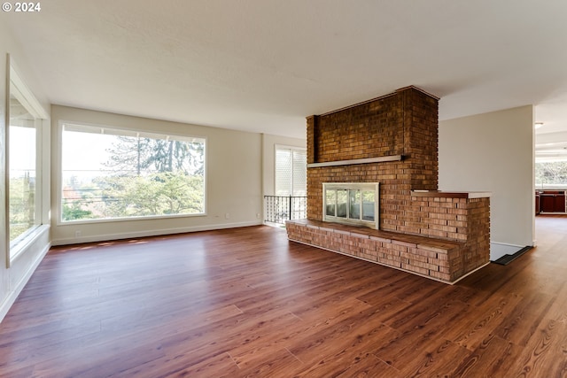 unfurnished living room with a brick fireplace, baseboards, and dark wood-style flooring