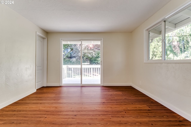 unfurnished room featuring a wealth of natural light, baseboards, and wood finished floors