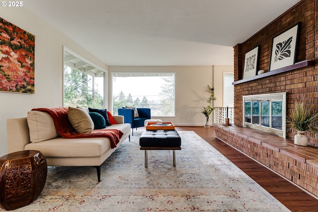 living area featuring a fireplace, baseboards, and wood finished floors