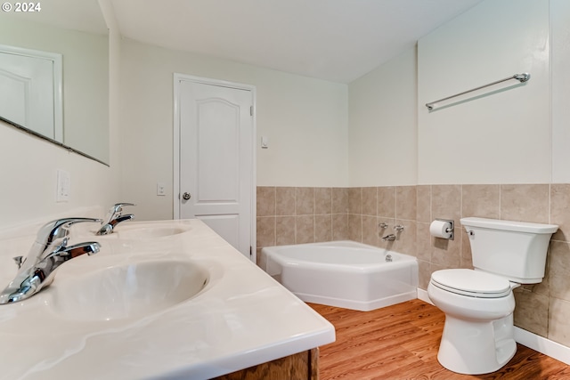 full bath featuring toilet, wood finished floors, a sink, tile walls, and a bath